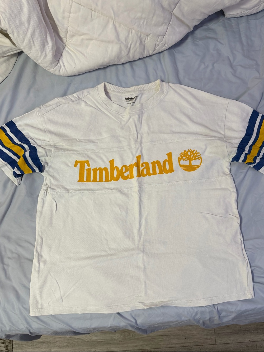 Timberland White Short Sleeve Tee with Yellow Logo and Blue Stripe Accents